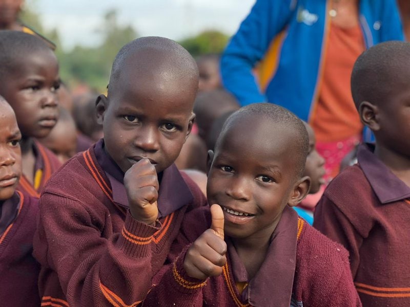 Mehrere Kinder aus dem Lichtstahl Projekt in Uganda Zwei Kinder heben den Daumen und schauen zur Kamera.